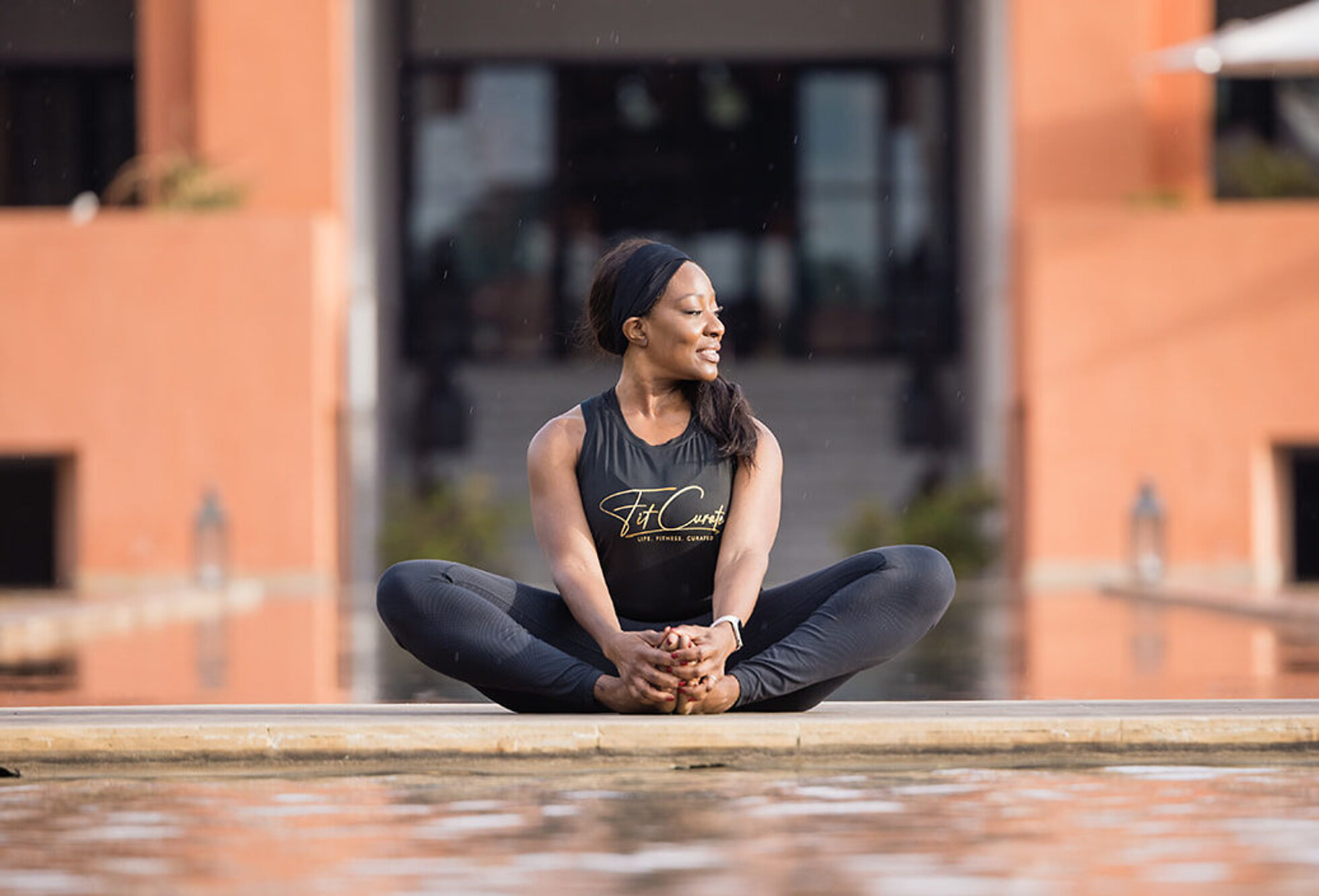 Wande O. seated by the courtyard pool — FitCurate